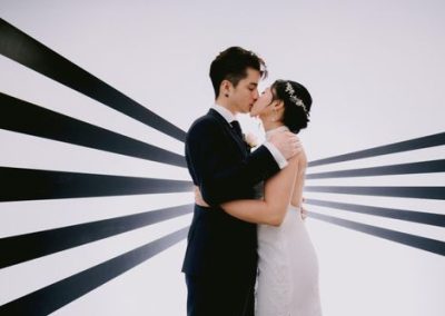 63079b08165a07a865943cad_bride-and-groom-kissing-in-front-of-white-wall-with-lines (1)-p-500