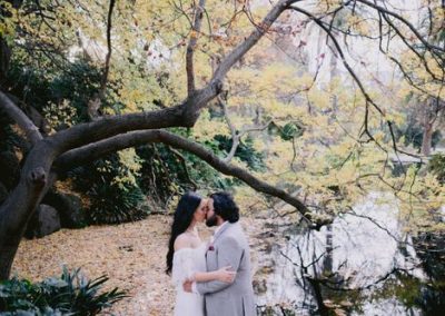 63079bb456390d19c975baee_bride-and-groom-kissing-under-autumn-tree-with-yellew-leaves-in-front-of-lake (1)-p-500